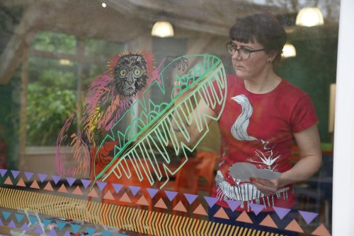 Artist Nikki Pinder drawing a lemur on a window
