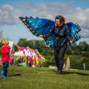 A member of staff at Chester Zoo in a butterfly costume interacts with a child in a red coat