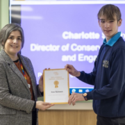 Teenage boy recieves certificate from adult female in grey suit