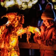 A young girl interacts with an orangutan puppet at Chester Zoo's Lanterns and Light
