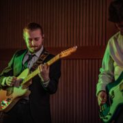 Two men play the electric guitar in a band during at party in The Square at Chester Zoo