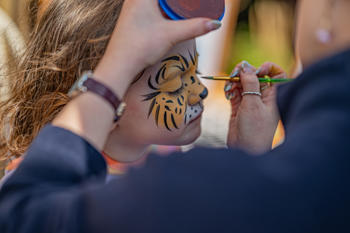 A child has their face painted into a cheetah pattern