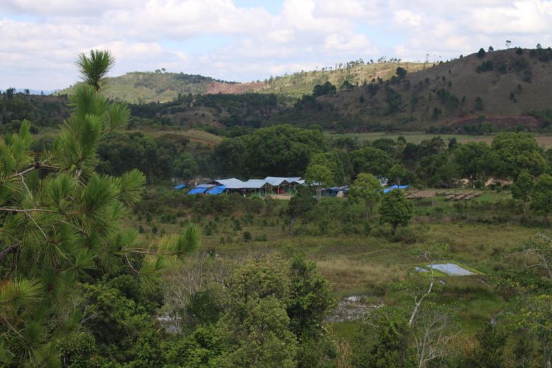 Image shows a wide shot of a wooded landscape with a few buildings and camping area at the centre, where MV work from