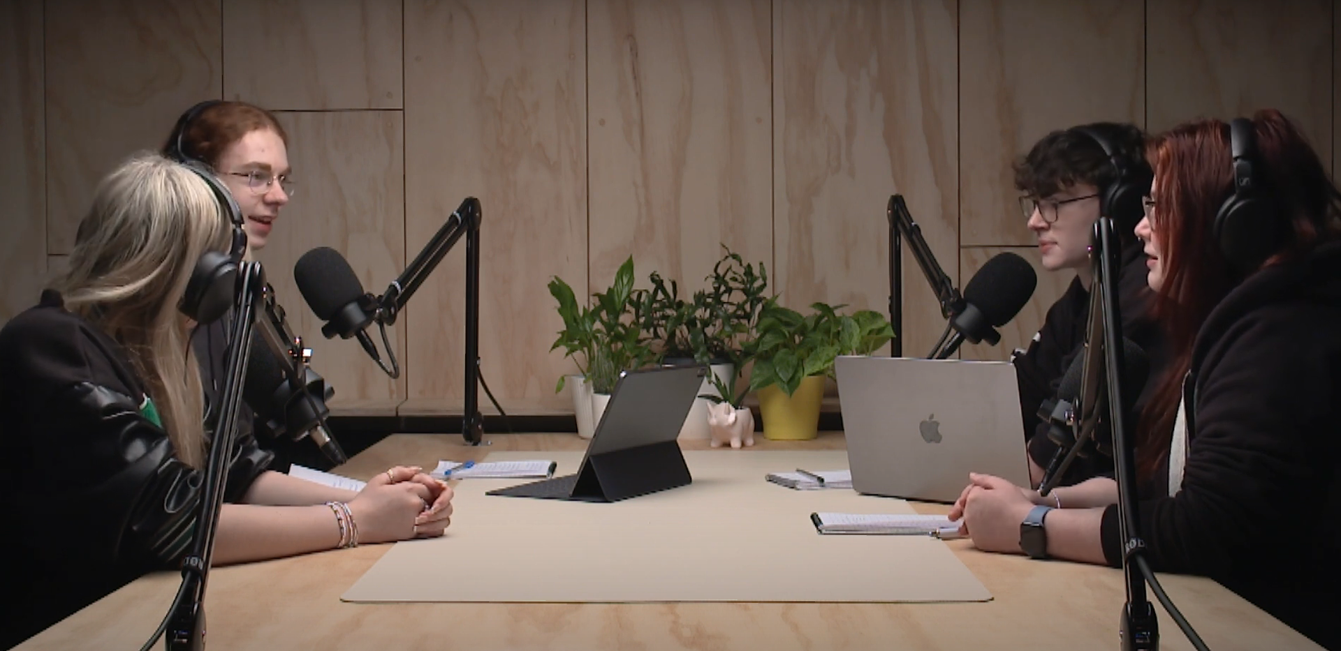 Photo shows young people speaking into microphones in a recording studio