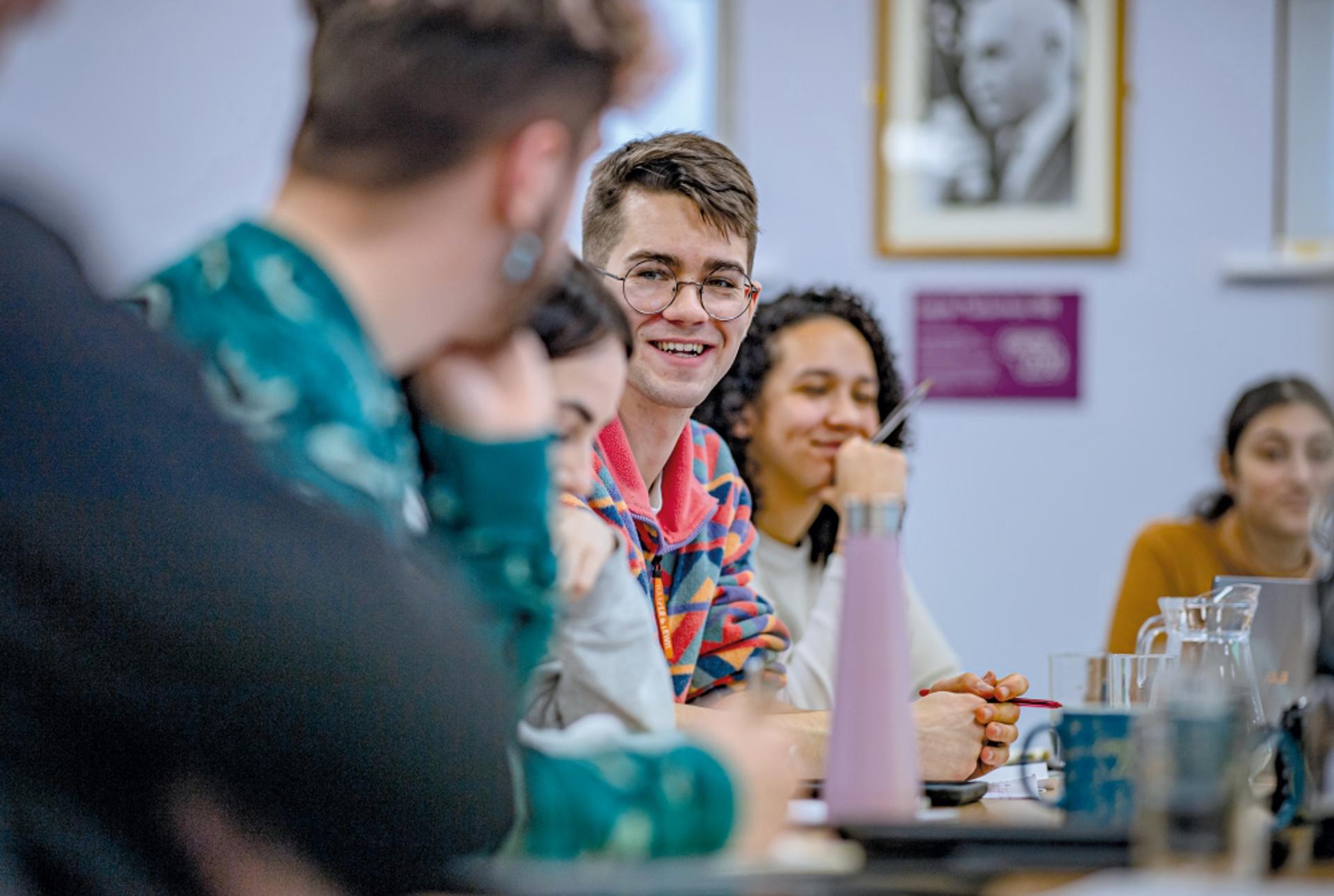 A photo showing young people sitting in a board room while holding a discussion