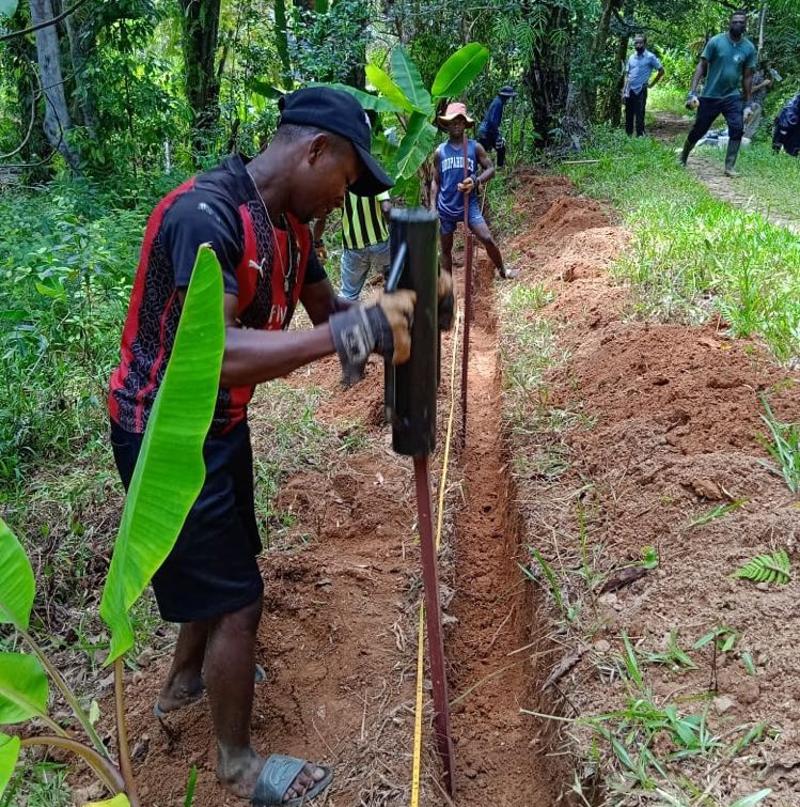 Image shows Malagasy workers putting a toad exclusion fence in place, near a ditch.